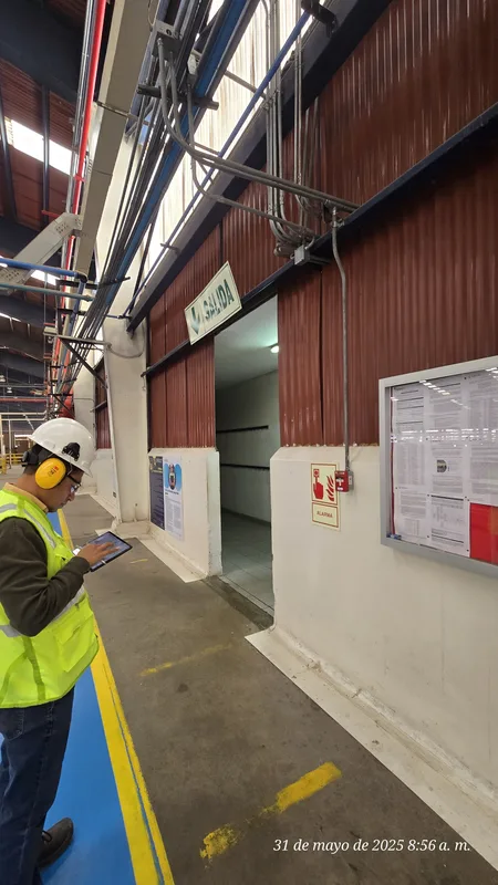 Subestación con puerta SALIDA, pulsador ALARMA y técnico tomando datos con tablet — cumplimiento normativo ITSE